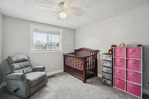 Carpeted bedroom featuring ceiling fan and a textured ceiling