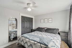 Carpeted bedroom featuring ceiling fan and a closet