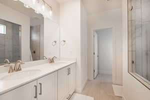 Bathroom with vanity, tiled shower, and wood-type flooring