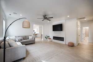 Living room with light hardwood / wood-style flooring and ceiling fan