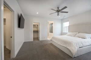 Carpeted bedroom with a spacious closet, ceiling fan, and a closet