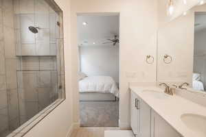 Bathroom featuring vanity, ceiling fan, and tiled shower