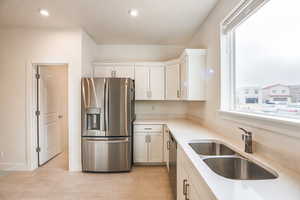 Kitchen featuring appliances with stainless steel finishes, sink, white cabinetry, and light wood-type flooring