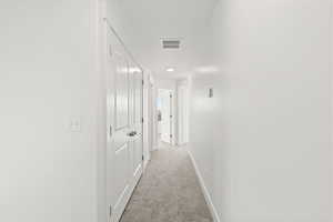 Corridor featuring light colored carpet