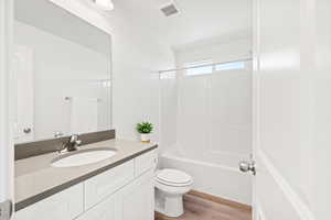 Full bathroom featuring vanity, hardwood / wood-style floors, washtub / shower combination, and toilet