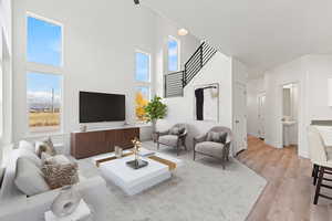 Living room with a towering ceiling and light hardwood / wood-style floors