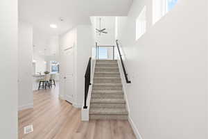 Stairs with ceiling fan and wood-type flooring