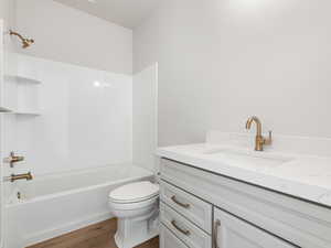 Full bathroom with vanity, hardwood / wood-style floors, shower / bathtub combination, and toilet