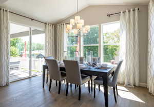 Dining area with lofted ceiling, hardwood / wood-style floors, and a notable chandelier