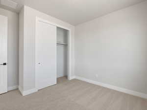 Unfurnished bedroom featuring light carpet and a closet