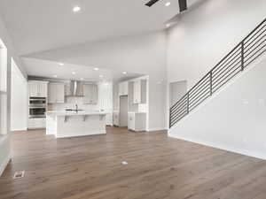 Unfurnished living room featuring high vaulted ceiling, dark hardwood / wood-style floors, sink, and ceiling fan