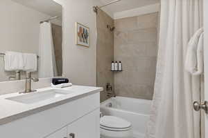 Full bathroom with shower / bathtub combination with curtain, vanity, and toilet