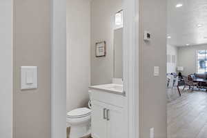 Bathroom featuring vanity, a textured ceiling, wood-type flooring, and toilet