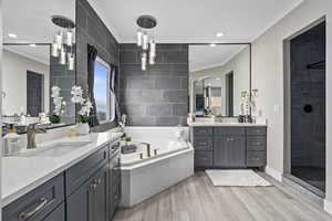 Bathroom with tile walls, vanity, wood-type flooring, ornamental molding, and separate shower and tub