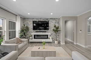 Living room featuring crown molding, a fireplace, and light hardwood / wood-style floors