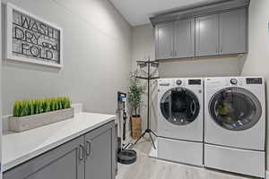 Laundry room featuring washer and dryer, cabinets, and light wood-type flooring