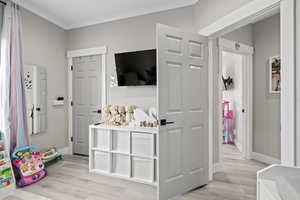 Interior space with crown molding and light hardwood / wood-style flooring