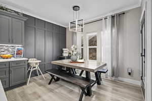 Dining space with crown molding, light hardwood / wood-style flooring, and a notable chandelier