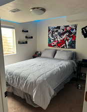 Carpeted bedroom with a textured ceiling