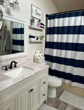 Bathroom featuring a shower with curtain, vanity, and toilet