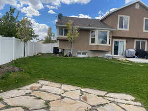 Back of property with central AC, a yard, and a patio