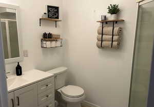 Bathroom with vanity, walk in shower, and toilet