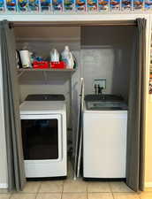 Washroom with light tile patterned floors and washing machine and dryer