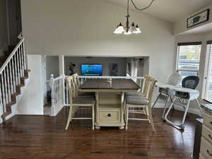 Dining area featuring dark wood-type flooring, high vaulted ceiling, and a notable chandelier