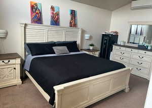 Carpeted bedroom featuring vaulted ceiling and a wall mounted air conditioner