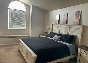 Bedroom with vaulted ceiling and light colored carpet