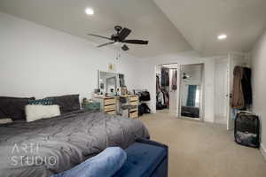 Carpeted bedroom featuring ceiling fan, a walk in closet, a closet, and a textured ceiling