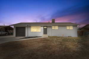 Single story home featuring a carport, a garage, and a lawn