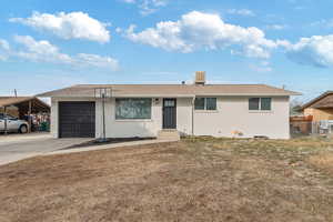 Ranch-style house featuring a carport, a garage, and a front lawn