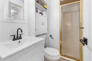 Bathroom featuring vanity, a shower with shower door, and toilet