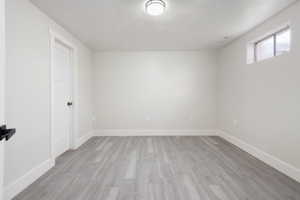 Empty room with a textured ceiling and light wood-type flooring