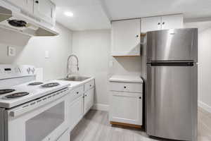 Kitchen featuring sink, white cabinets, stainless steel refrigerator, and electric stove