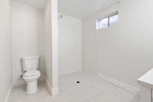 Bathroom with a tile shower, tile patterned floors, and toilet