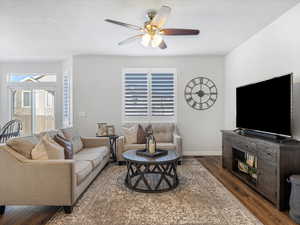 Living room with ceiling fan and dark hardwood / wood-style flooring