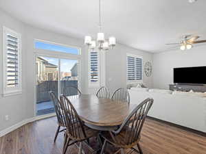 Dining space with dark hardwood / wood-style flooring and ceiling fan with notable chandelier