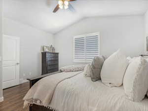 Bedroom with vaulted ceiling, dark hardwood / wood-style floors, and ceiling fan