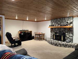 Living room with a fireplace, wooden ceiling, and carpet flooring