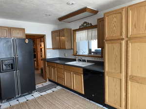 Kitchen with tasteful backsplash, sink, black appliances, and a textured ceiling