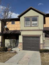 View of front of property with stone siding, stucco siding, concrete driveway, and a garage