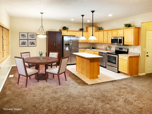 Kitchen with sink, appliances with stainless steel finishes, hanging light fixtures, a kitchen island, and light carpet