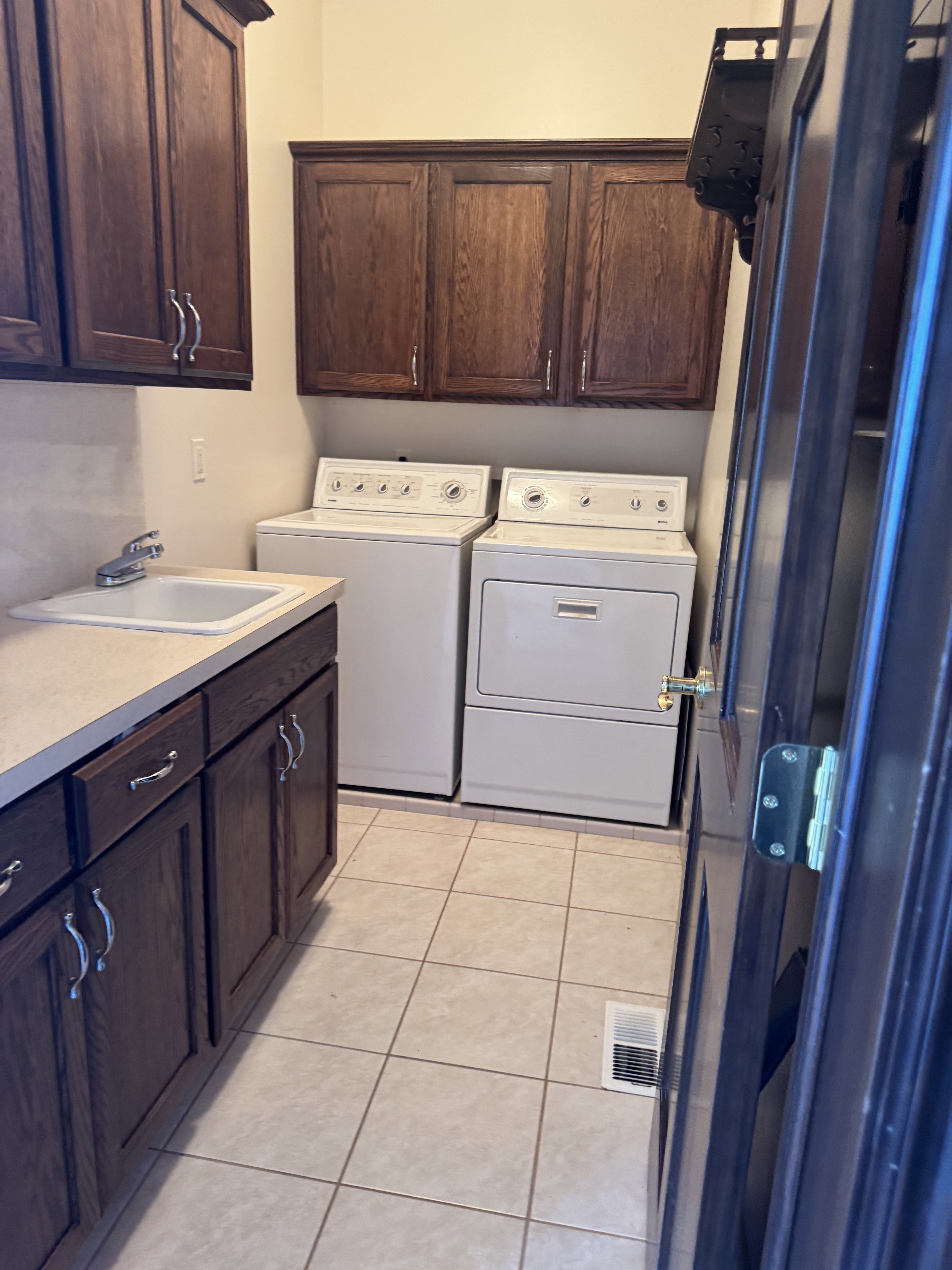 Laundry room with built in cabinets for linens a utility sink and included washer and dryer