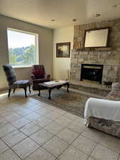 Living area with a textured ceiling, a fireplace, and light tile patterned floors