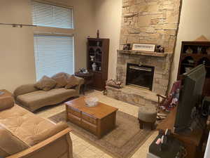 Living room with a stone fireplace and light tile patterned floors