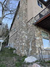 View of side of property featuring stone siding, a balcony, and stucco siding