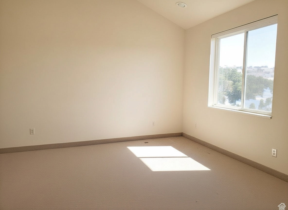 Neutral tone walls and carpeting throughout a room with a large window