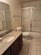 Bathroom featuring light tile patterned floors, combined bath / shower with glass door, and vanity